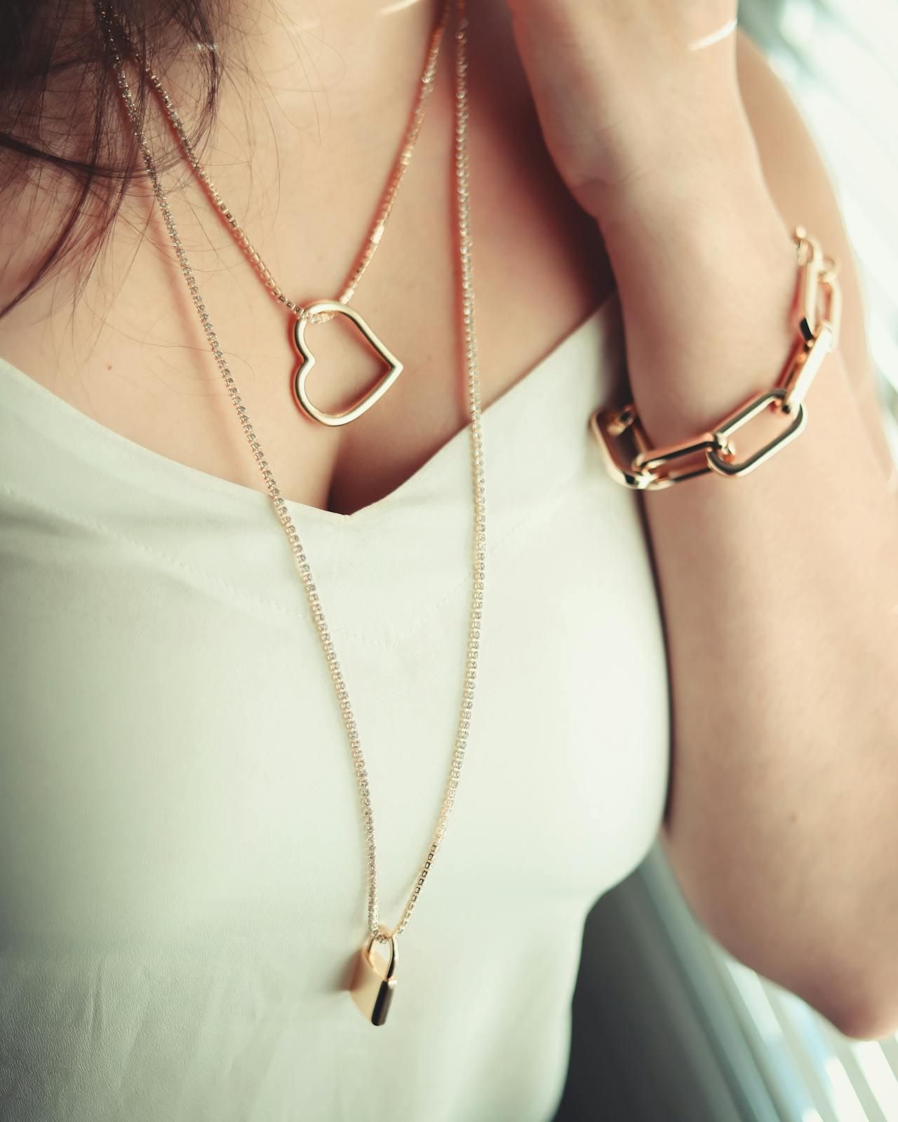 Close-up of sparkling diamond rings, gold and platinum bracelets, and gemstone necklaces on soft fabric with cleaning tools nearby, set against a neutral backgr